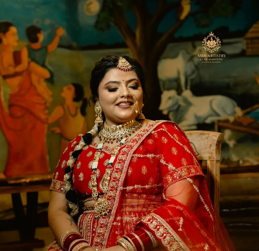 Bridal portrait in a red lehenga against a heritage painted backdrop