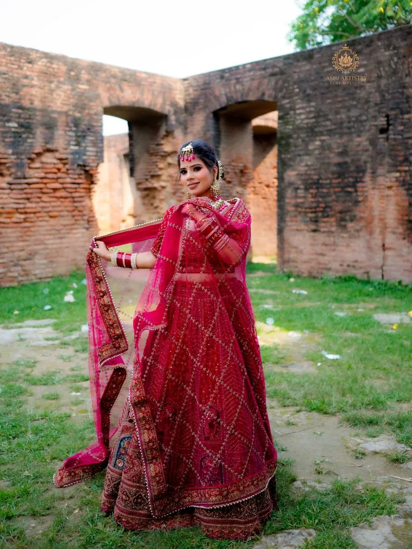 Bride twirling her dupatta on a lawn near a heritage archway